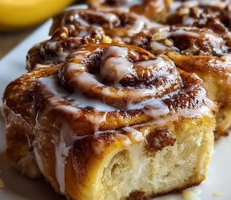 1735855500050-b33rq64b Delicious banana bread cinnamon rolls topped with icing and cinnamon sugar.