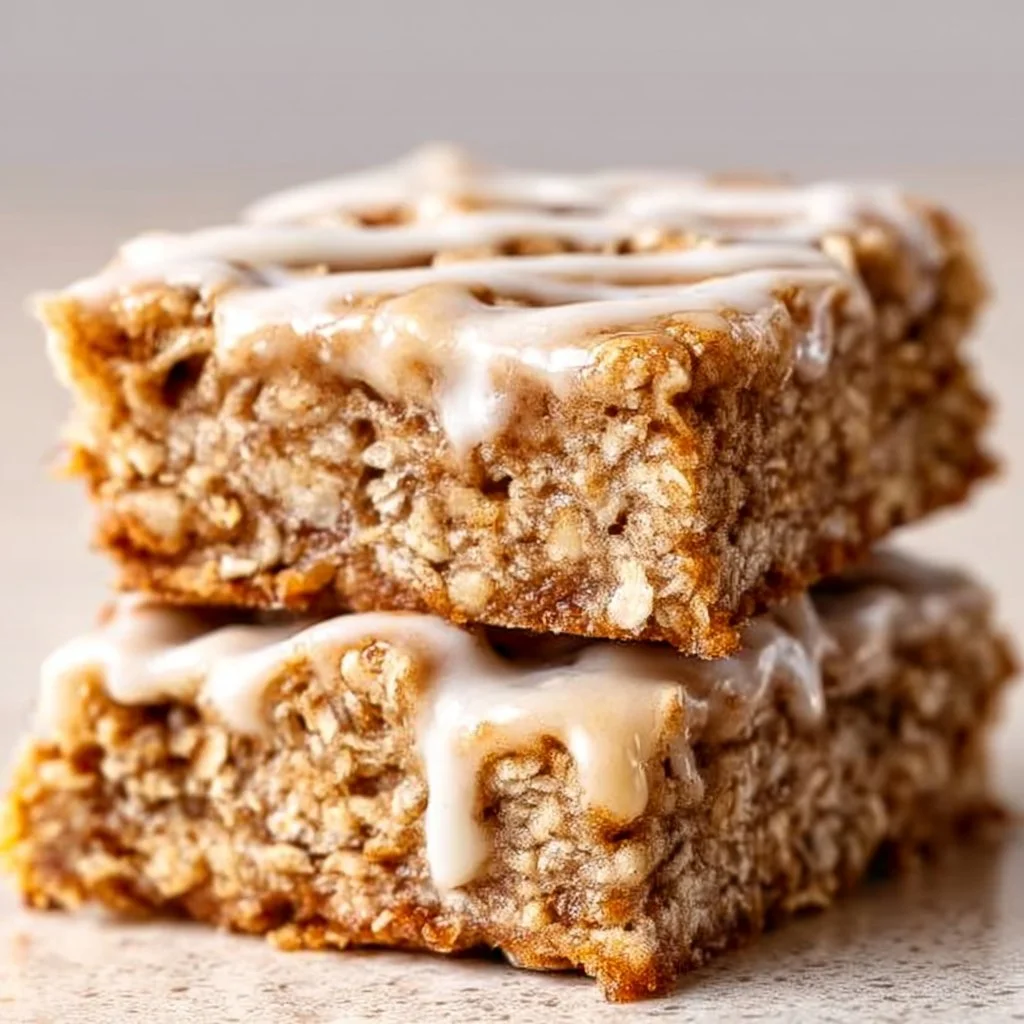 Delicious Cinnamon Roll Oatmeal Bars topped with icing on a wooden table