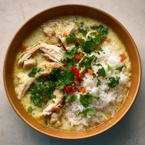 Bowl of Coconut Chicken Brothy Rice garnished with herbs and spices