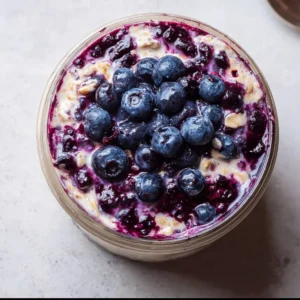 Blueberry pie overnight oats topped with fresh blueberries and cream