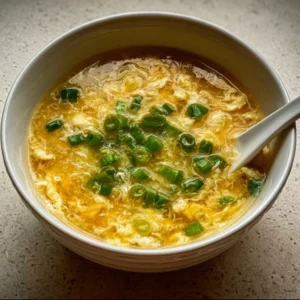 Bowl of homemade Egg Drop Soup with silky egg ribbons and green onions