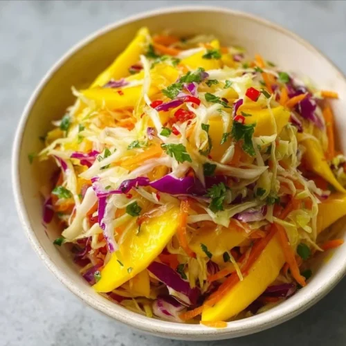 Colorful Mango Slaw with shredded vegetables and mango slices on a plate