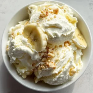 Delicious bowl of banana pudding ice cream topped with whipped cream and banana slices.