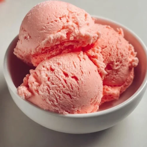 Creamy watermelon ice cream in a bowl, garnished with fresh mint leaves