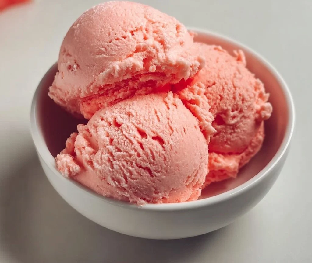 1735855500050-b33rq64b Creamy watermelon ice cream in a bowl, garnished with fresh mint leaves